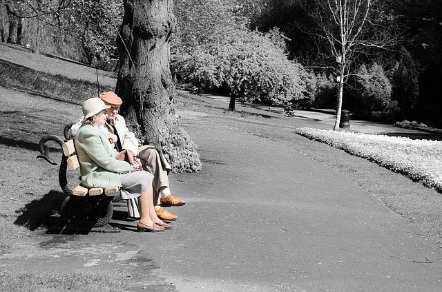 Starší manželský pár sedící na lavičce v parku